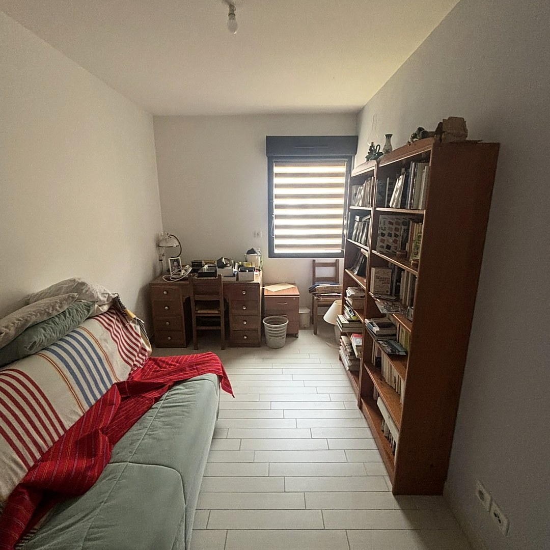 La même chambre avant intervention, avec canapé, bibliothèque et bureau.