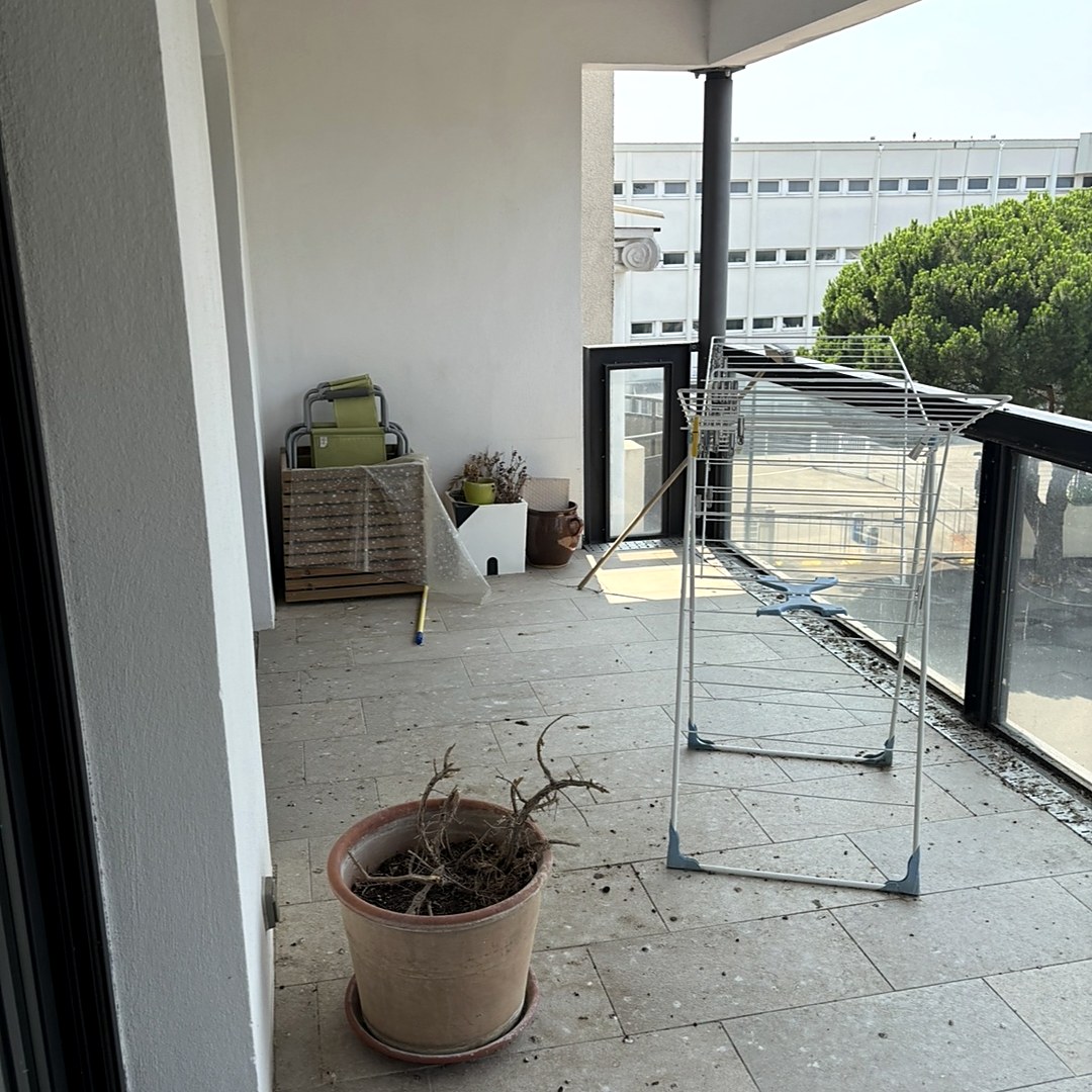La terrasse avant intervention : étendoir à linge déplié, pot de fleurs avec une plante morte, mobilier de jardin empilé contre le mur.